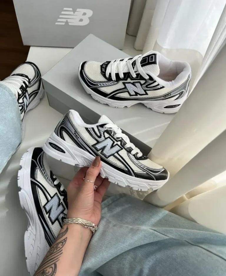 Zapatillas New Balance 740 blancas y negras en mano sobre caja – Total Look BZ